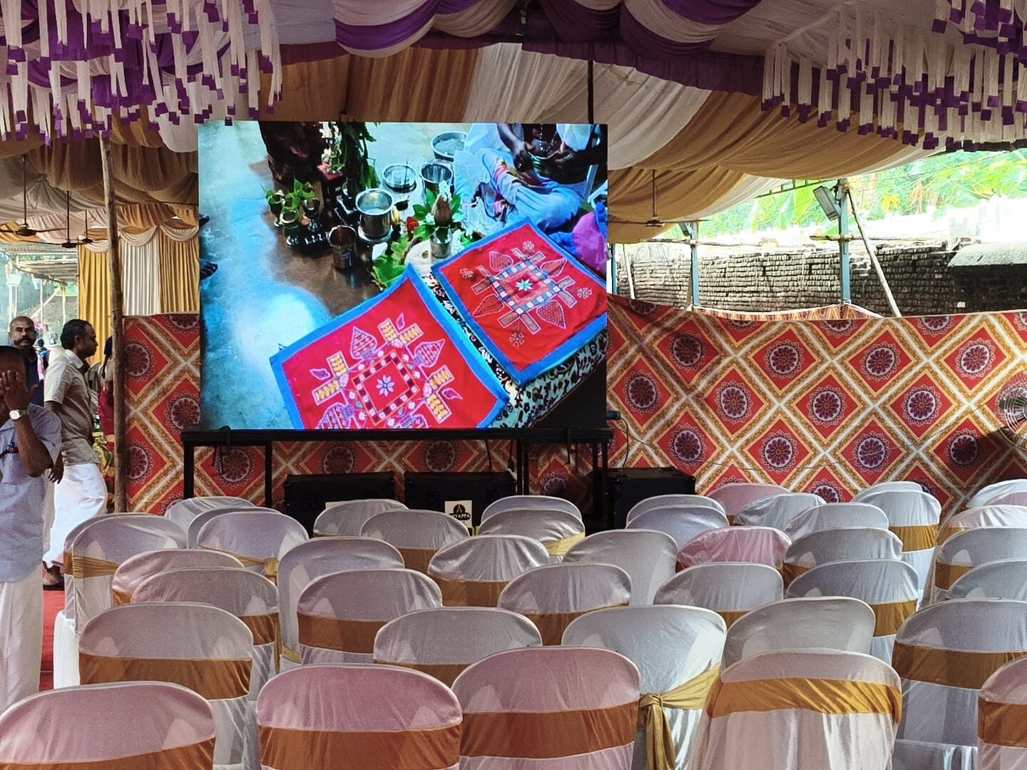 LED wall under a decorated event tent with chairs